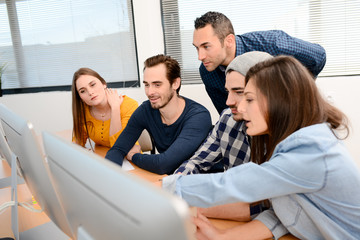 group of five young people student with teacher in computer school classroom learning programming with desktop computer in a row