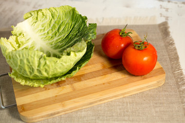 fresh white cabbage tomatoes on a wooden board on a gray background
