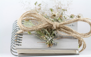 Flowers and notebooks are tied together with rope.
Old memories but it's someone's happiness.