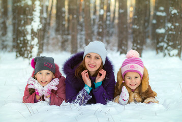 Children play with mom in winter. Two daughters and mom