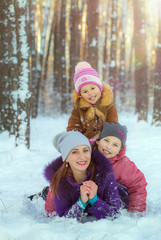Children play with mom in winter. Two daughters and mom