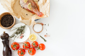 Cooking and marinating sea fish at home. Red perch with lemon, pepper and rosemary lies on parchment paper.