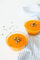 Two plates of pumpkin soup with seeds on a white background with space for your text.