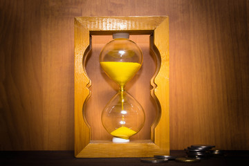 The glossy old-style hourglass standing with a coins