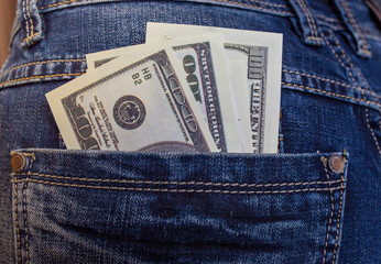 American dollars, hundred-dollar notes, sticking out of the blue jeans pocket. Pocket in blue jeans with hundred and more US dollar. Business concept exchange