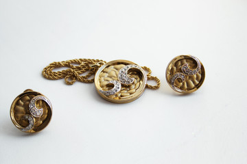 Gold plated earrings and pendant on a white background