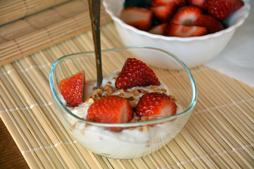 Cream cheese dessert with slices of strawberry on a glass bowl. Healthy snack.