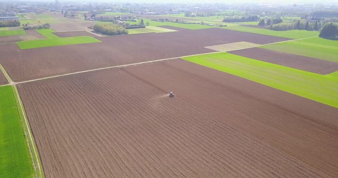 Trattore che ara i campi, vista aerea di un campo arato ed un trattore che semina. Agricoltura e coltivazione, campagna