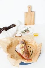 Cooking and marinating sea fish at home. Red perch with lemon, pepper and rosemary lies on parchment paper.