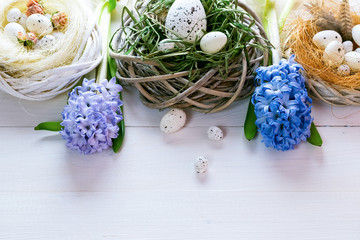 Beautiful Easter eggs in nest with flowers on the wooden background