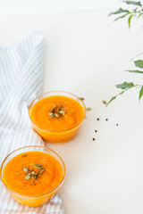 Two plates of pumpkin soup with seeds on a white background with space for your text.