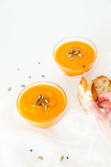Two plates of pumpkin soup with seeds on a white background with space for your text.