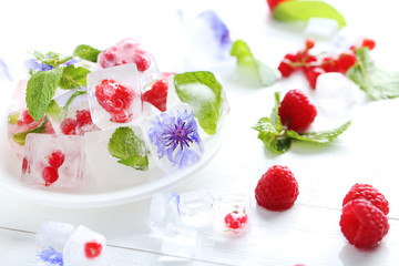 Ice cubes with raspberries and mint leaf on wooden table