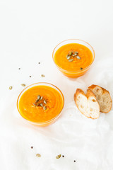 Two plates of pumpkin soup with seeds on a white background with space for your text.