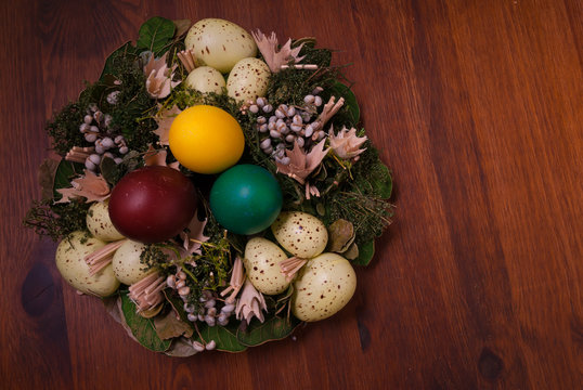 Colorful Easter eggs stacked in decorative garland on a brown table