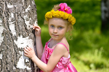 Girl in a pink dress in a wreath of dandelions