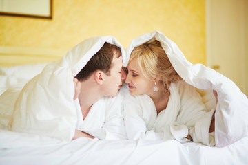 Couple in white bathrobes in bed