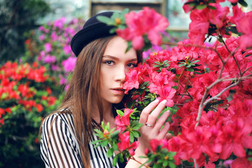 Tender sweet young woman enjoying azalea flowers in greenhouse