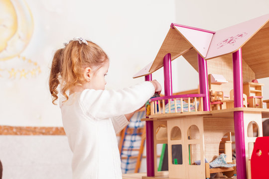 Girl Playing With A Dollhouse