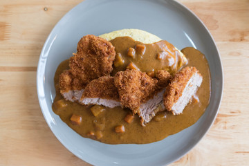 Omelette Rice with Japanese Curry and Breaded Deep Fried Pork Cutlet on Modern Wood Table