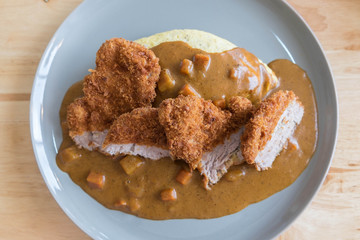 Omelette Rice with Japanese Curry and Breaded Deep Fried Pork Cutlet on Modern Wood Table