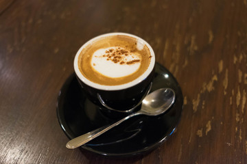 Obraz na płótnie Canvas Black Cup of Hot Cappuccino Coffee with a tea spoon