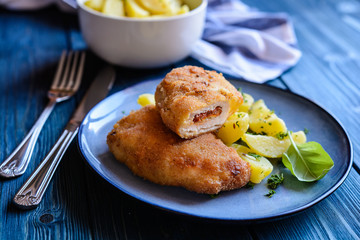 Fried pork cutlets stuffed with sun - dried tomato and Roquefort cheese, served with potato