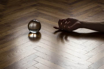 Crystal fortune-telling ball placed on wooden floor with human hand