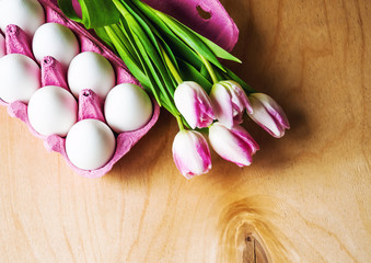Easter eggs and pink tulips on wooden background, copy space blank for text - Easter festive background, top view, flat lay