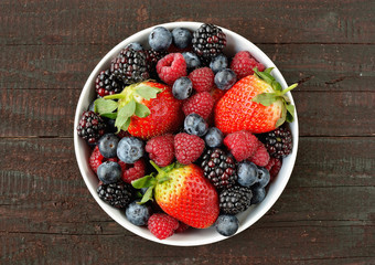 Mix of strawberries, blueberries, blackberries and raspberries fruit on wood table. Forest fruit in white idaeus. Delicious fresh berries.