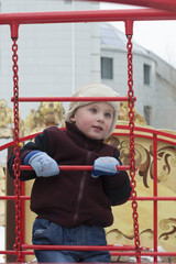 The happy little boy plays on the playground in the winter