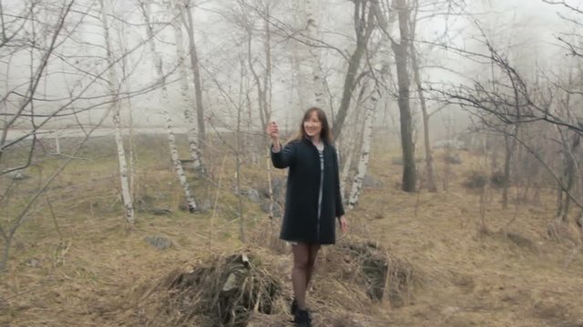 Young woman throws paper airplane handheld mid shot. Paper airplane Beautiful young woman walking through a foggy forest. Kazakhstan.