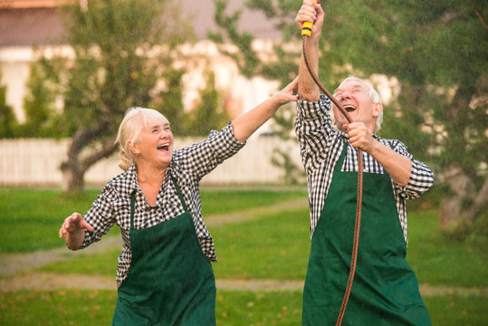 People having fun, garden hose. Cheerful old couple outdoors.