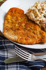 Fried pork chop in breadcrumbs, served with vegetable salad.