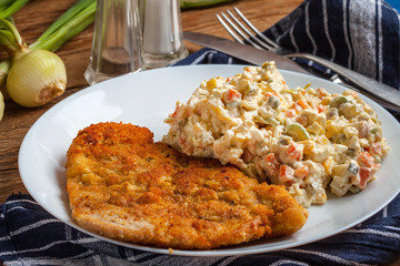 Fried pork chop in breadcrumbs, served with vegetable salad.