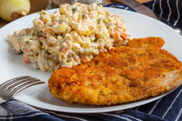 Fried pork chop in breadcrumbs, served with vegetable salad.