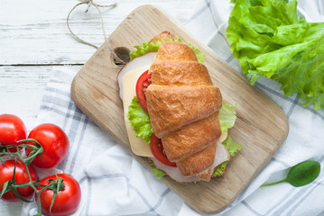 Croissant sandwich with bacon, cheese, lettuce and tomato
