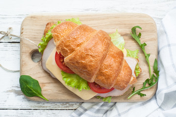 Croissant sandwich with bacon, cheese, lettuce and tomato. Top view