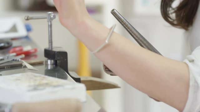  Jewelry designer working in studio using a tool to work on a ring. 
