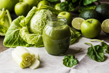 Detox diet. Green smoothie with different vegetables on wooden background