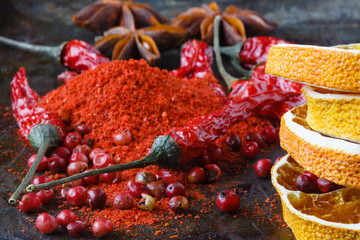 Fototapeta na wymiar Closeup red pepper with ground paprika on dark
