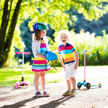 Kids riding scooter in summer park.