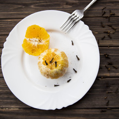 Baked orange with spices - cinnamon, cloves and cardamom. On a white plate. With a smartphone