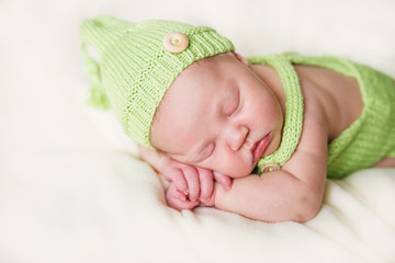 Newborn baby sleeping in knit green hat.