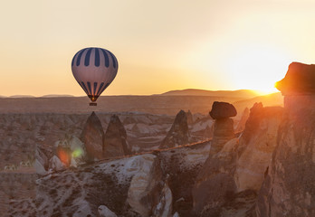 hot air balloon rises very high in blue sky above white clouds, bright sun shines