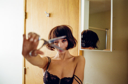 Woman plays with scissors in black bra