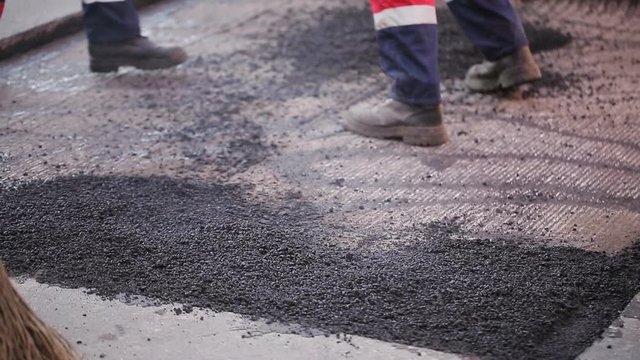 Workers asphalt a damaged section of the road.