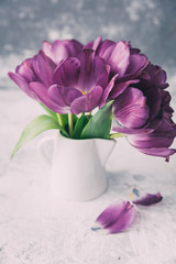 Fresh pink tulip flowers bouquet on shelf in front of stone wall. View with copy space
