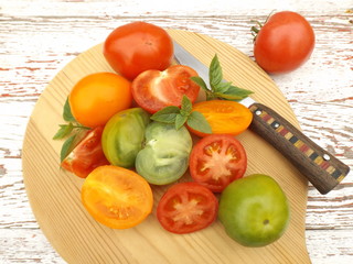 Tomatoes of different varieties cut on a wooden board