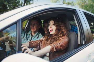 Girl driving a car and a guy inside ride on the road